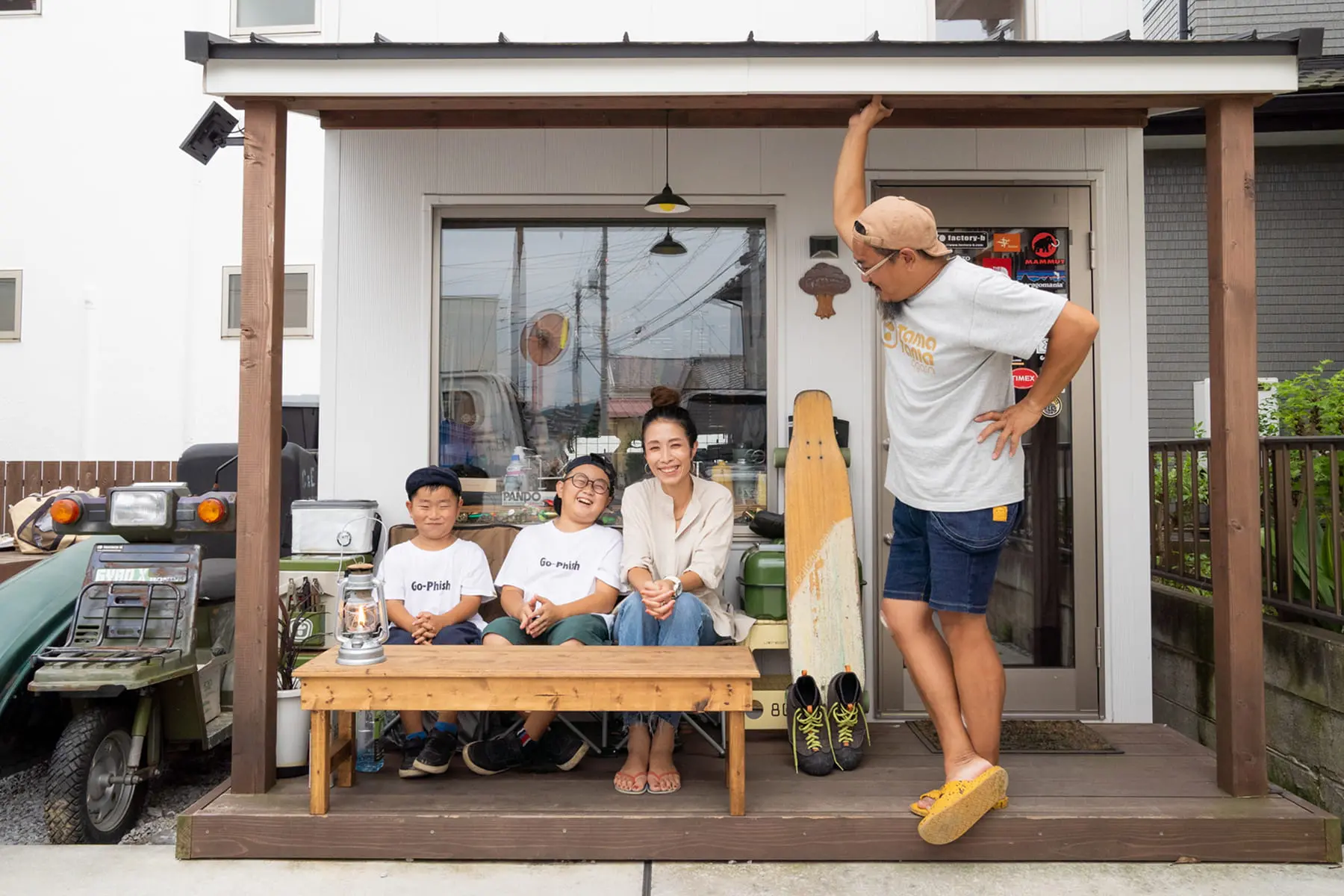 玄関前のウッドデッキでくつろぐ笑顔の家族