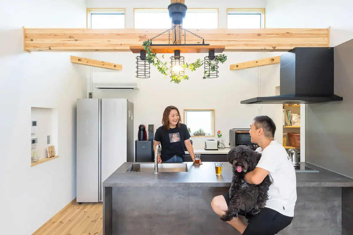 キッチンで愛犬を抱きながら談笑する夫婦